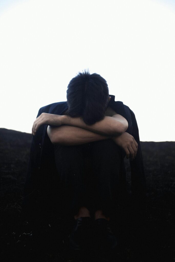 Image of a man with his head in his arms.