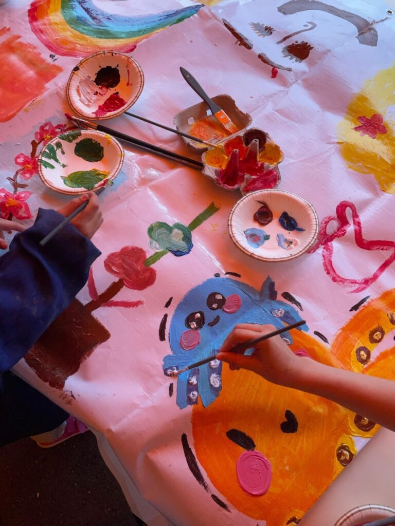 The hands of children paint colorful figures.