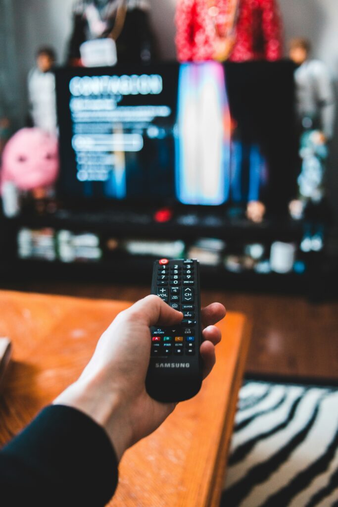 Image of a person pointing a remote control at a tv.