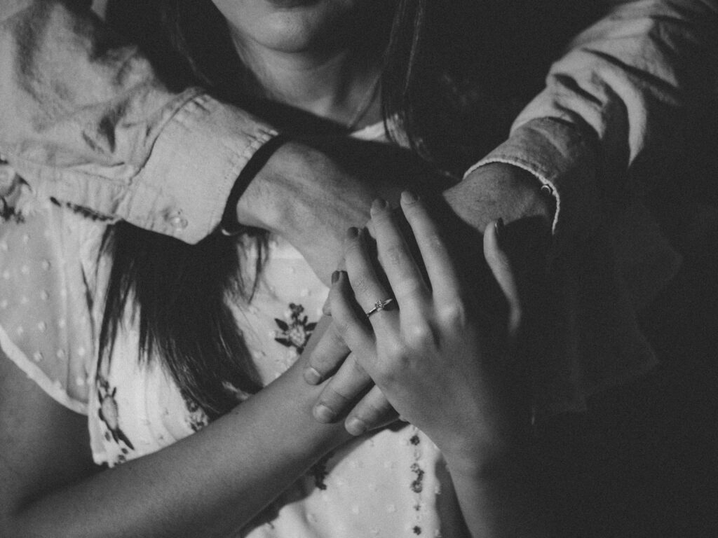 A girl holding the hands of an older woman from behind.