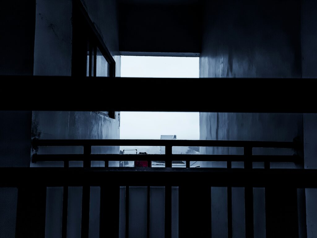 A lonely corridor with high steel bars and a murky gray sky in the background.