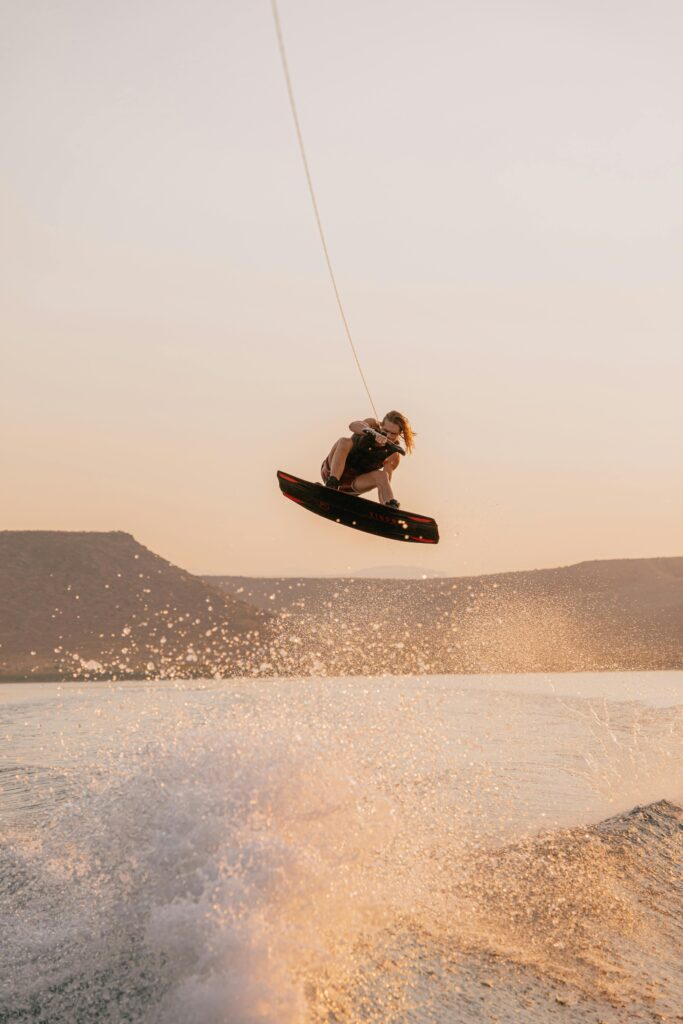 Photo of a long-haired man high above the water on a wakeboard.