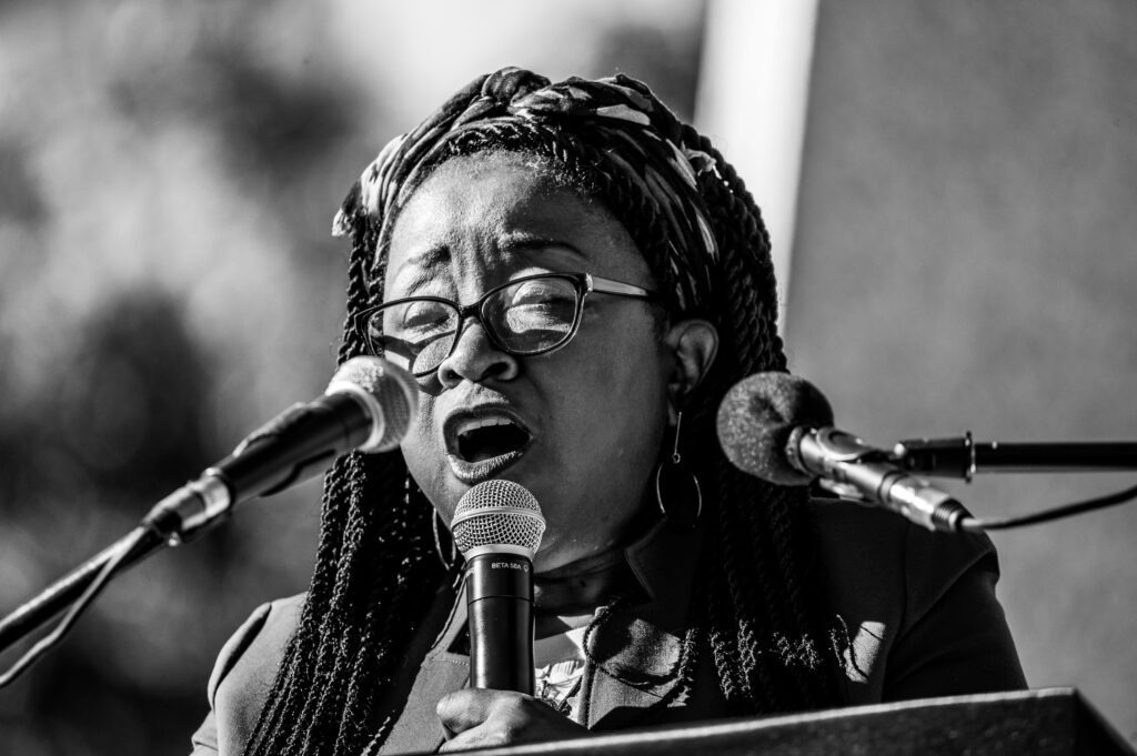 A black woman speaks powerfully while multiple microphones convey her important message!