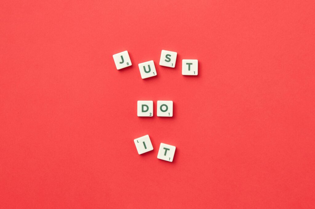 Scrabble tiles on a red background spelling out “Just do it.”