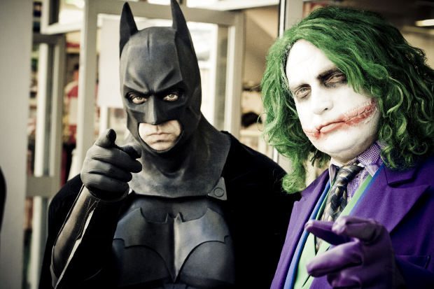 characters dressed as Batman and the Joker point at the camera
