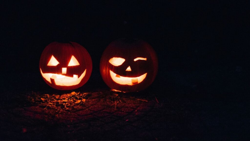Two jack-o-lanterns glowing in the dark.