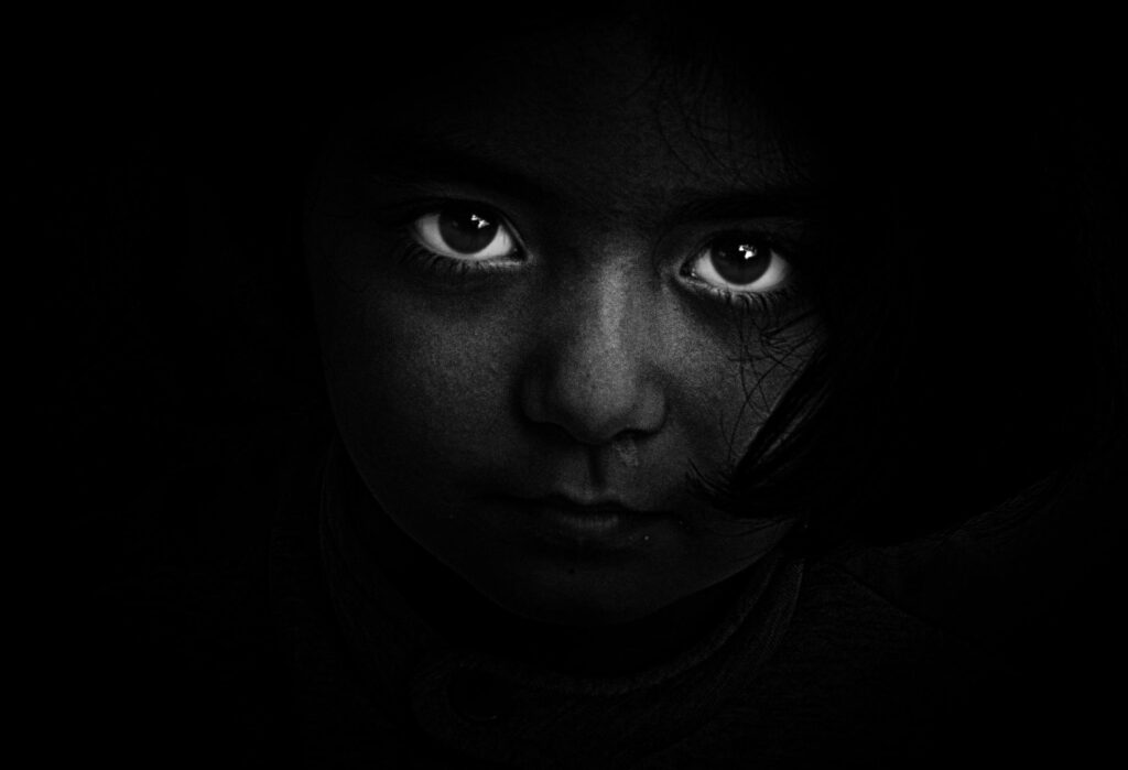 A face sits in blackness; all you can see are the whites of their eyes.