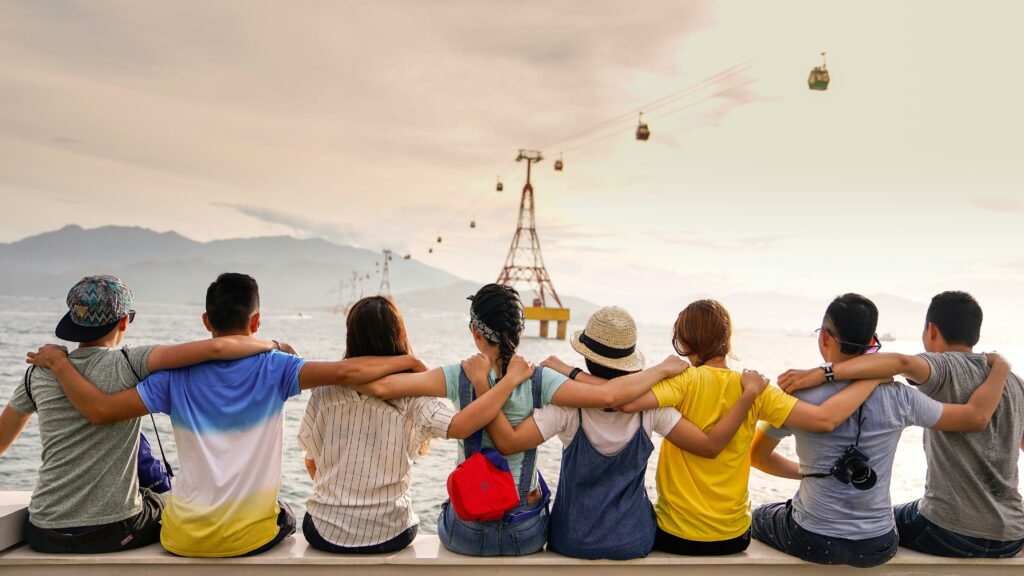 A group of friends, arms linked, looking over a body of water with a buoy bobbing in the distance.