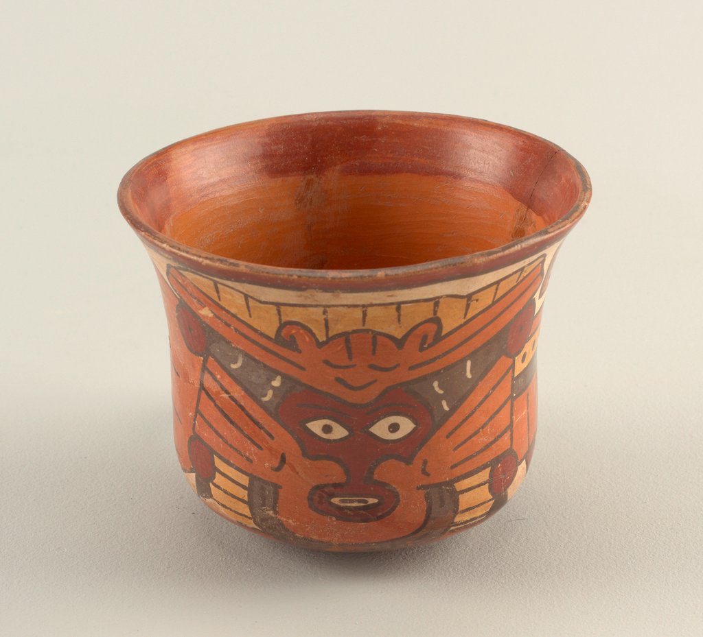 Earth-toned orange-brown-yellow-tan ceramic beaker with a shocked-looking human face framed by a self-satisfied bat with outstretched wings.