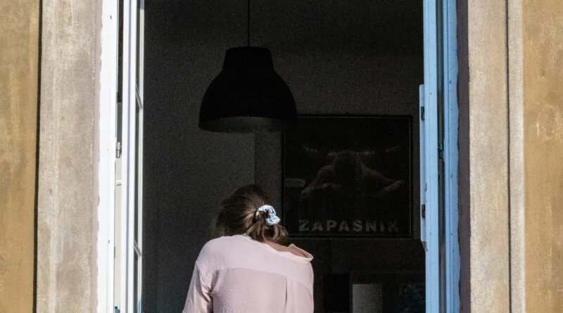 Woman sitting in front of an open window in the room of an old house.