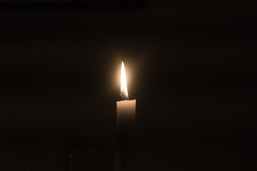 Image of a candle burning in the dark.