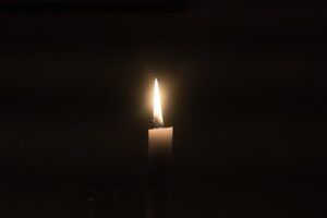 Image of a candle burning in the dark.