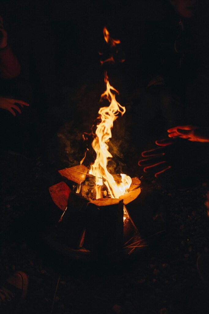 Hands in a circle all extending toward a fire.
