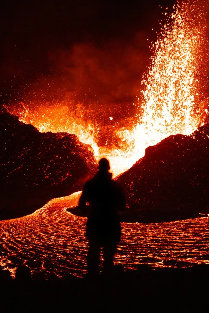 A person stands among erupting lava fields.