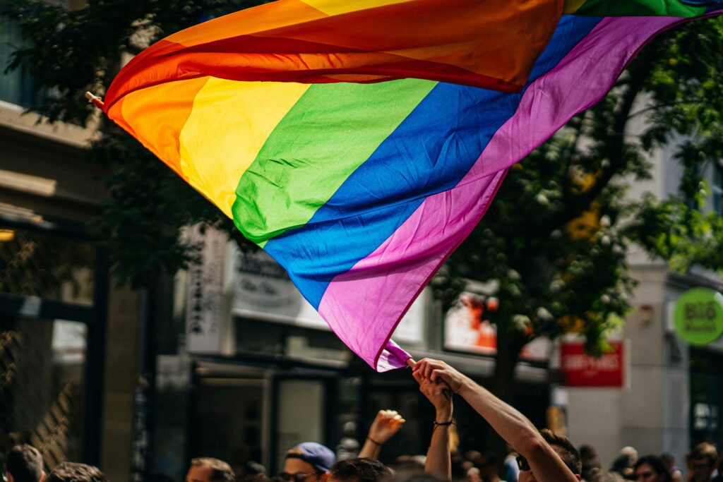Arms waving a glowing pride flag in the wind