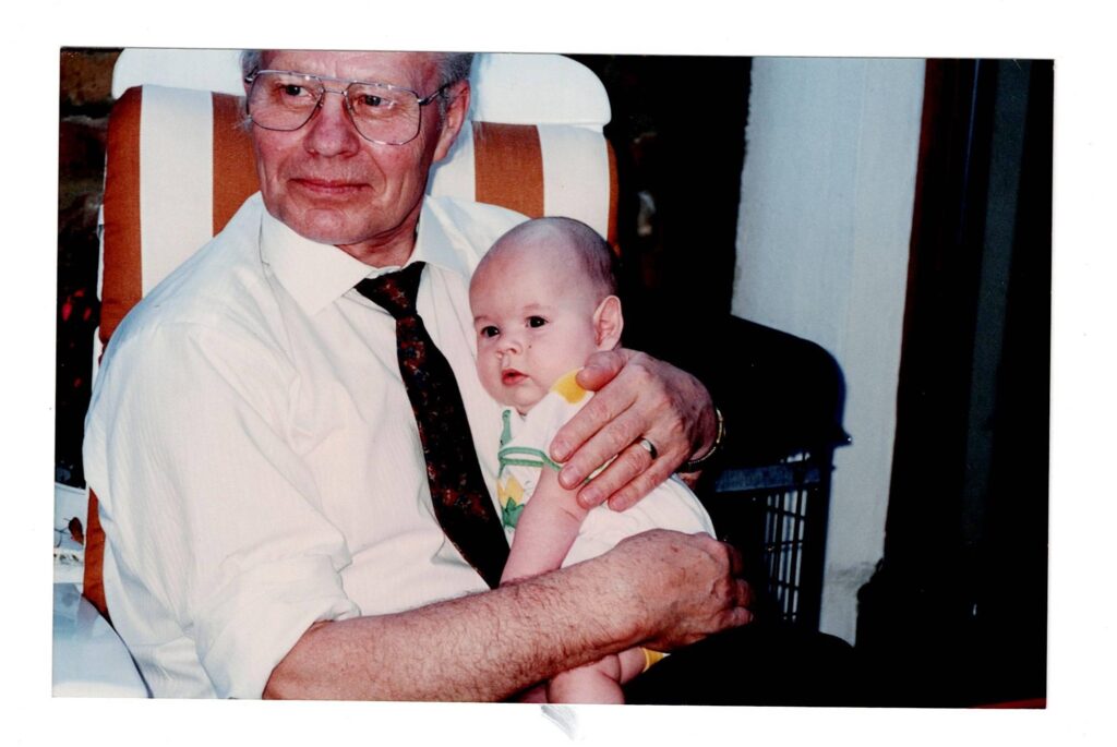 Smiling Grandpa ‘Dzadzio’ holding baby in his arms.