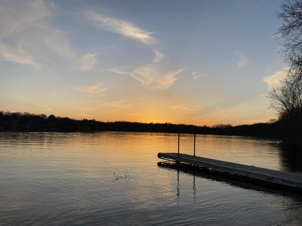 A dock over water, colored by the sunset. 
