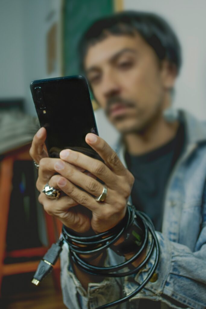 Man holding phone and handcuffed by its charging cord