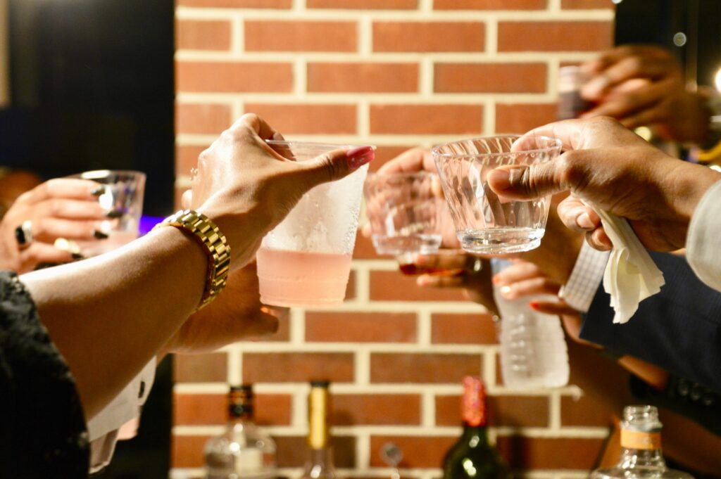 A group of individuals holding drinks, putting them together in a circle to ‘cheers.’