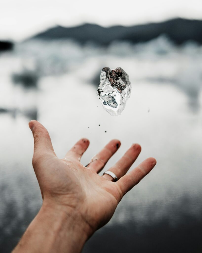 A large drop of water floating above an outstretched hand.