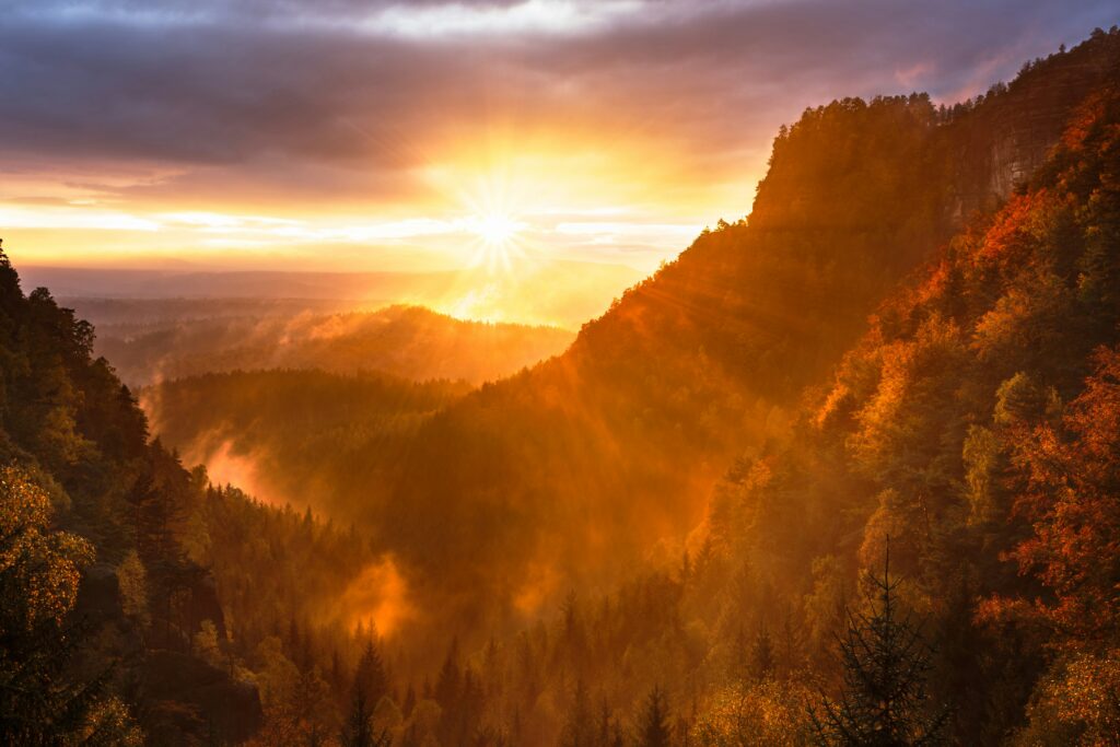 Image of the sun rising over mountains and valleys.