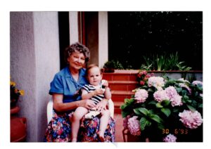 Smiling Grandma ‘Babcia’ in colorful clothing holding grandson.