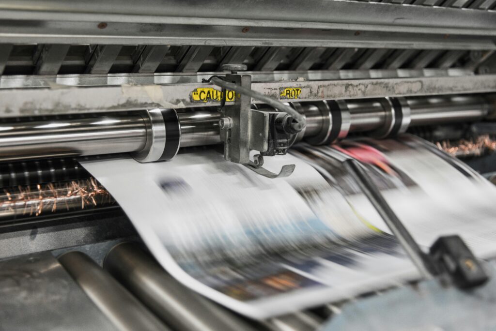 A newspaper quickly slides out of a printing machine.