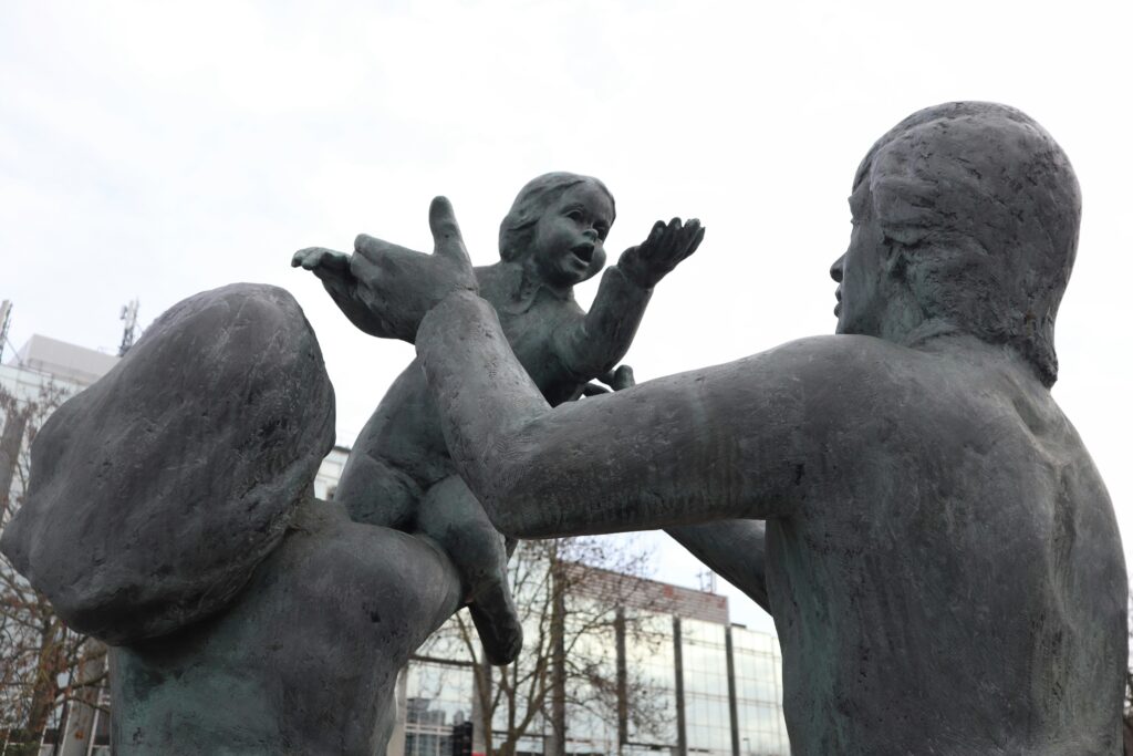 A statue of two parents playing with a child.