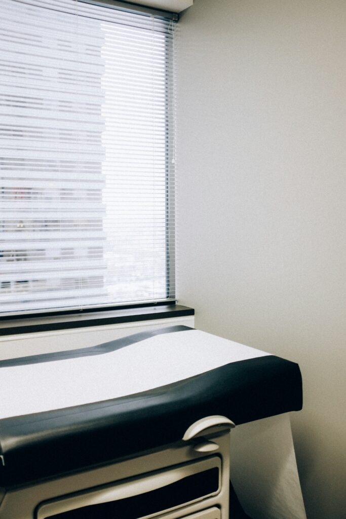 A physician’s room with an exam table under a window. 