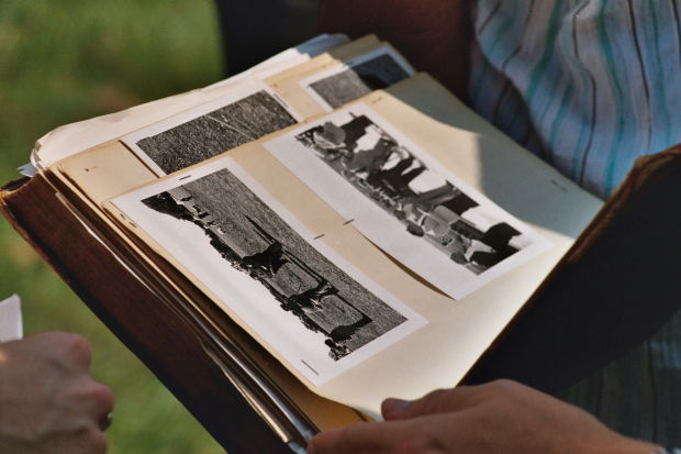 A person’s hand carefully browses old black and white photographs.