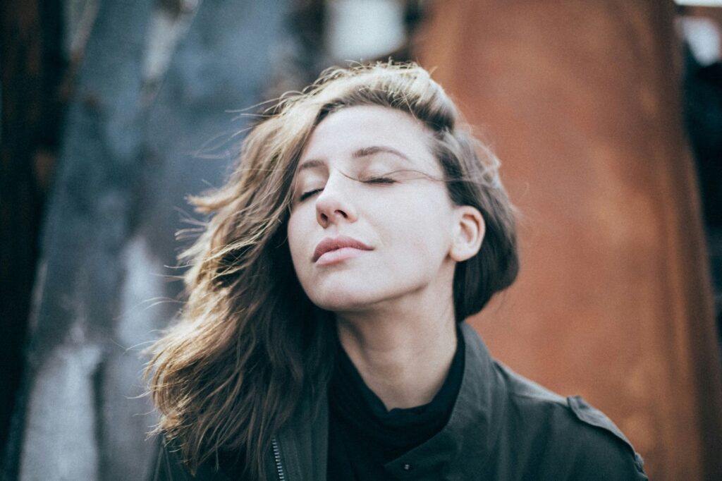 Image of a woman with her eyes closed, face tilted up towards the sky.