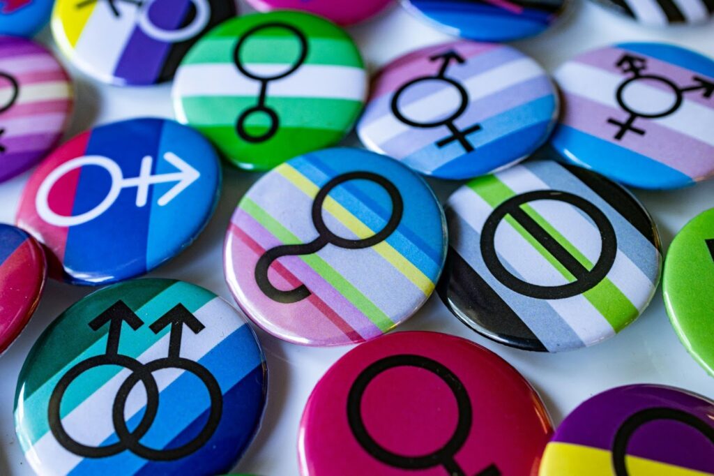 A pile of different colored buttons with gender symbols in black on them. 