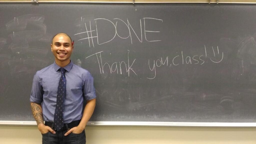 Author Jordan Luz stands in front of a chalkboard that reads, “#DONE Thank you, class :)” 