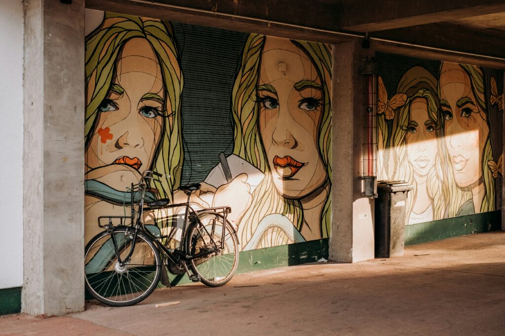 Murals of a woman’s face, with a bike leaning against one of the faces. 