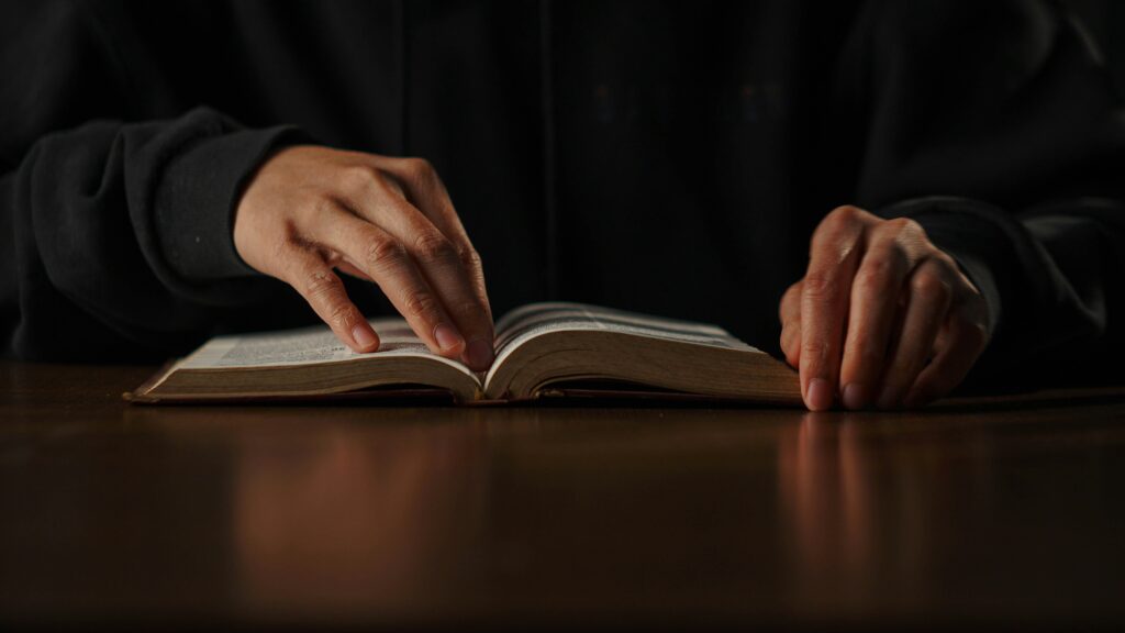 Image of a person reading a book at a table.