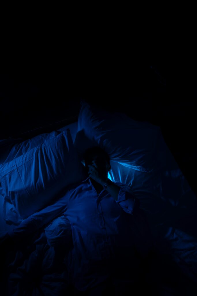 A person laying in a bed in a dark room.