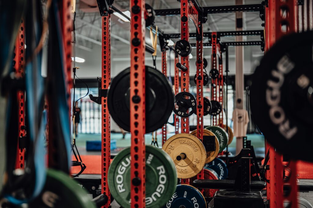 Multiple weight racks in a warehouse gym with various sizes of plates.