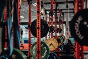 Multiple weight racks in a warehouse gym with various sizes of plates.