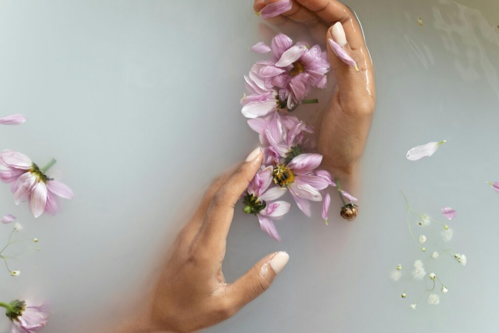 Hands and flowers floating in opaque water. 