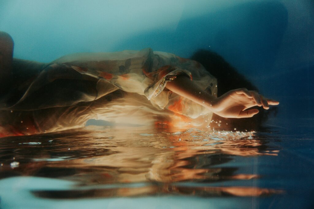 Image of a woman falling into water. She’s wearing a floral dress.
