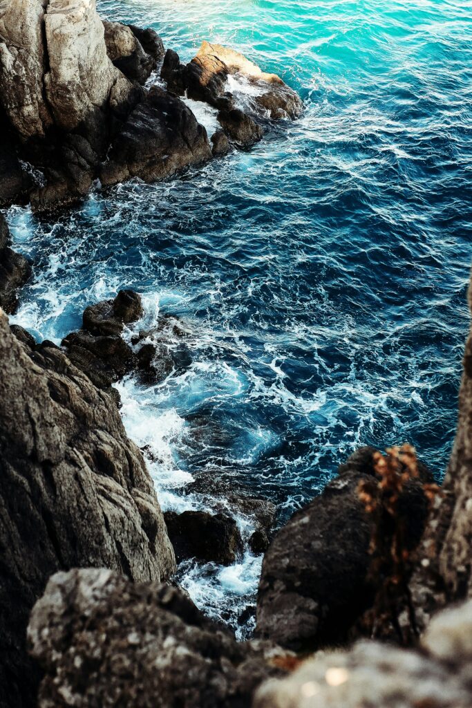 Image of waves crashing against rocky cliffs.