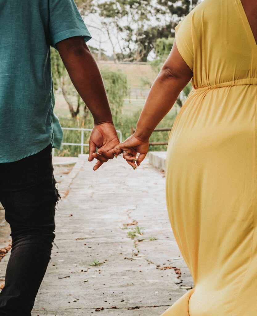 Man and woman holding hands walking down the street, viewed from the back
