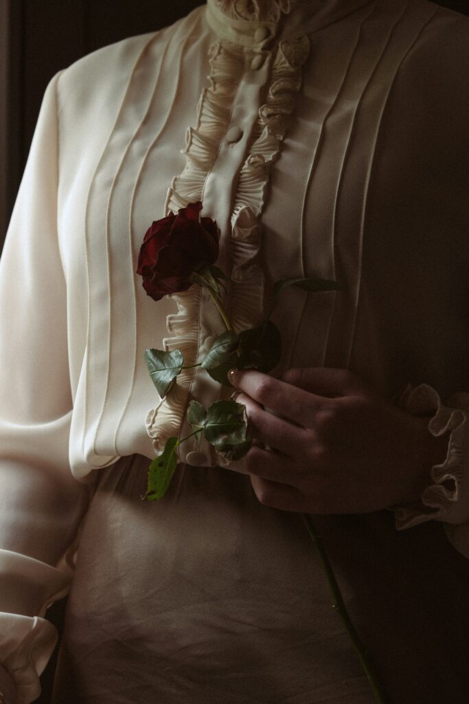 Old-fashioned woman hold a red rose.