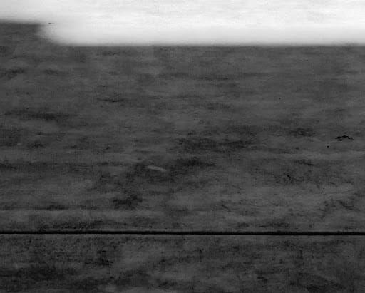 A dark gray landscape, barren and broken, with a haze in the air.