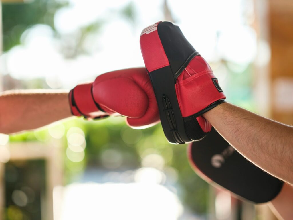 A person wearing a boxing glove punching into a focus mitt.
