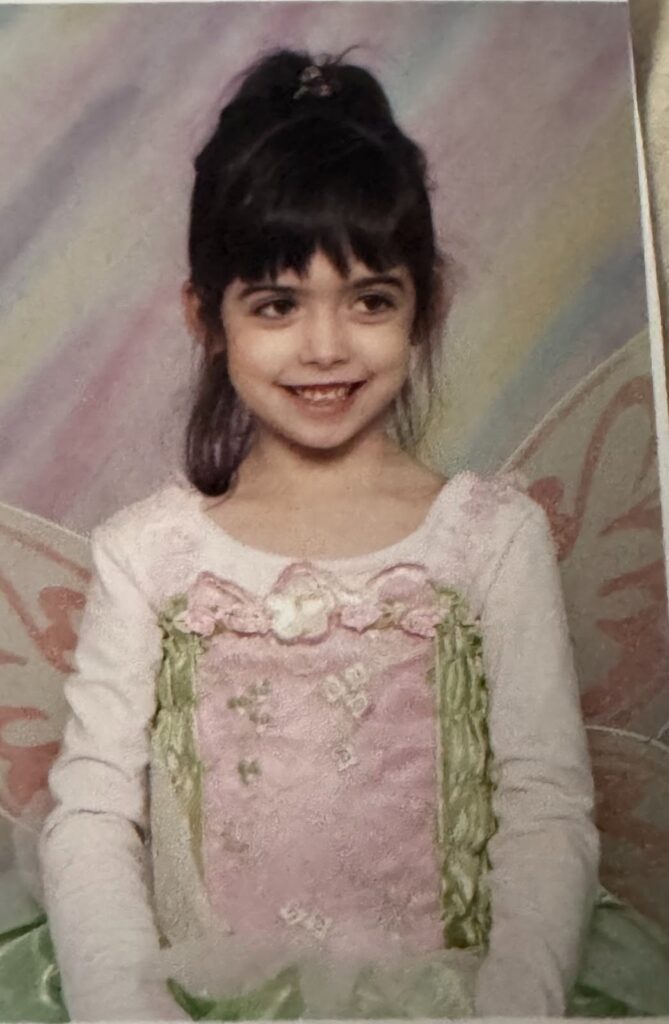 Professional photo of a five-year-old girl, smiling in a fairy Halloween costume.