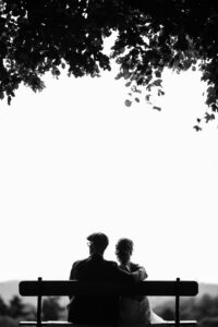 Two people sitting on a bench under a tree, enjoying the view.