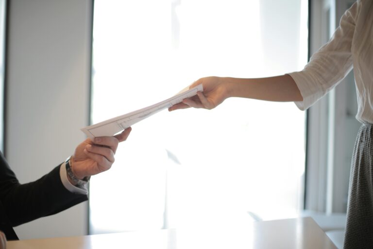 A woman hands her application documents to the interviewer.
