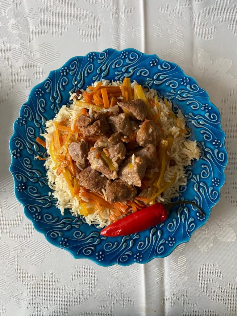 A decorative plate containing rice, meat and vegetables.