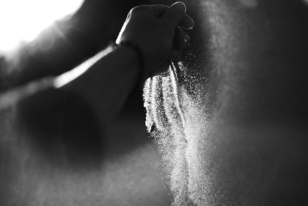 Image of a person’s clutched hand. Sand falls out of their hand as they loosen their grip.